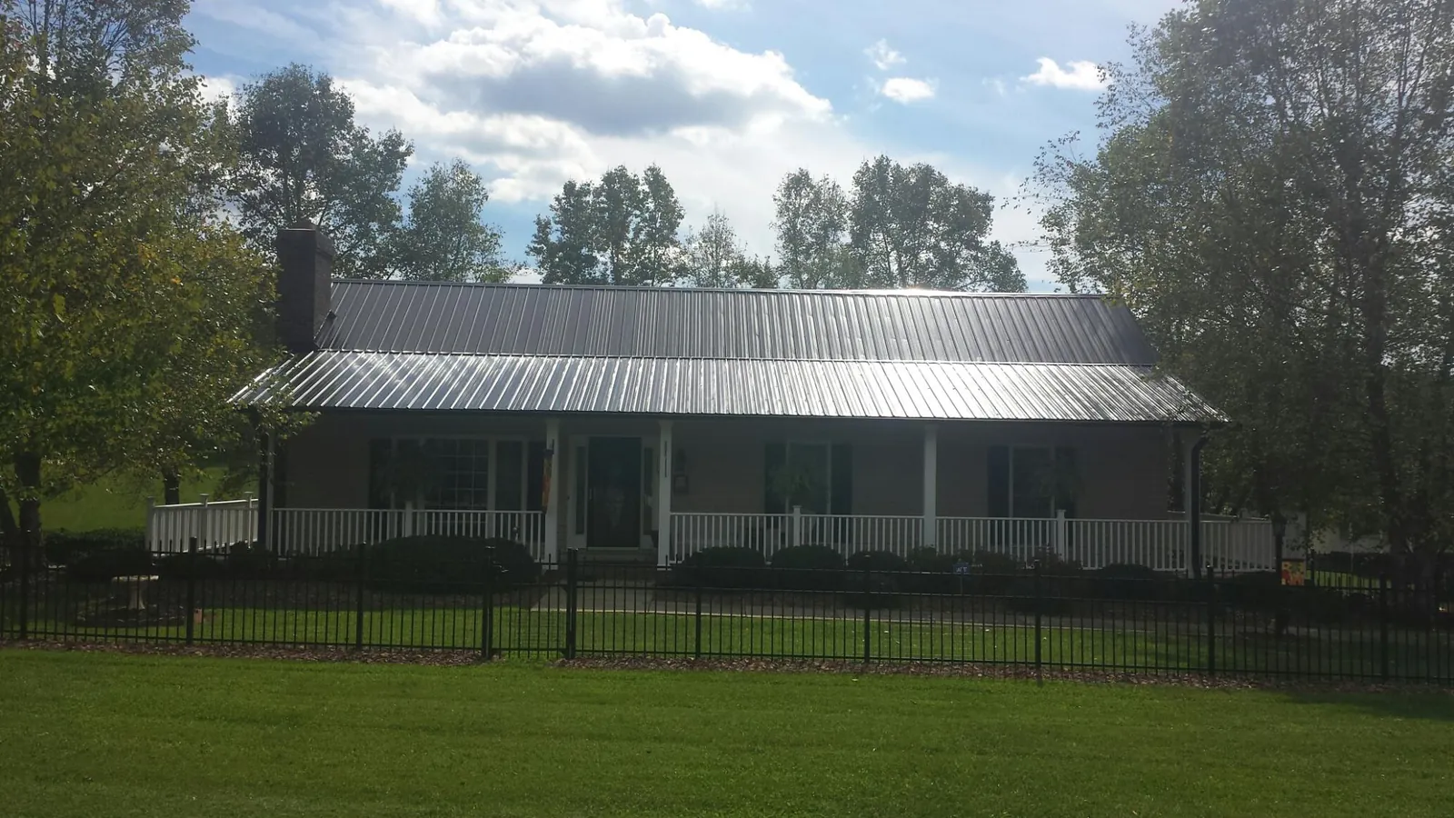 Gray metal roof on a brick ranch with a full width front porch — Gutter Guard Installation work by our crew in Hazel Park