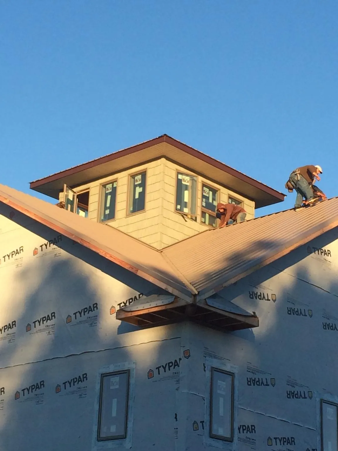 Roofers working around a rooftop cupola on a new metal roof at sunset — Roof Waterproofing in Hazel Park by Roofing Brothers